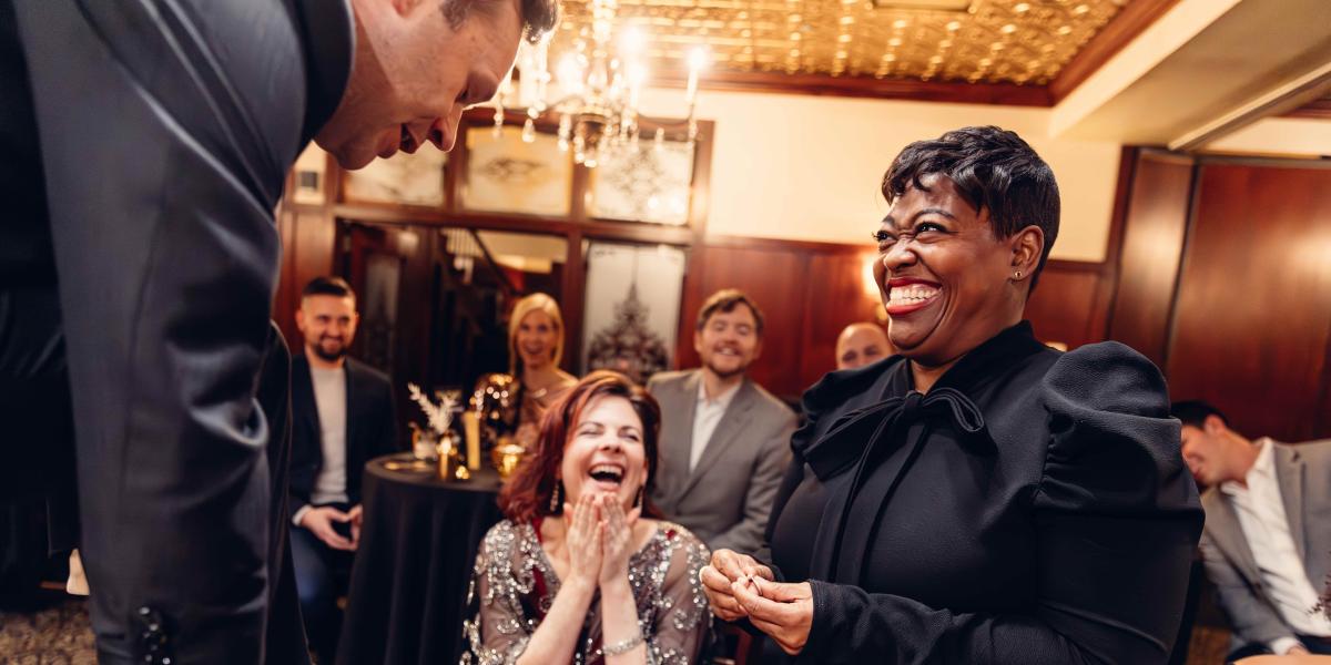 Guests laughing and smiling as Dennis performs magic. 