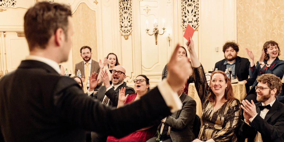 Audience member holds up an envelope as others respond with applause.