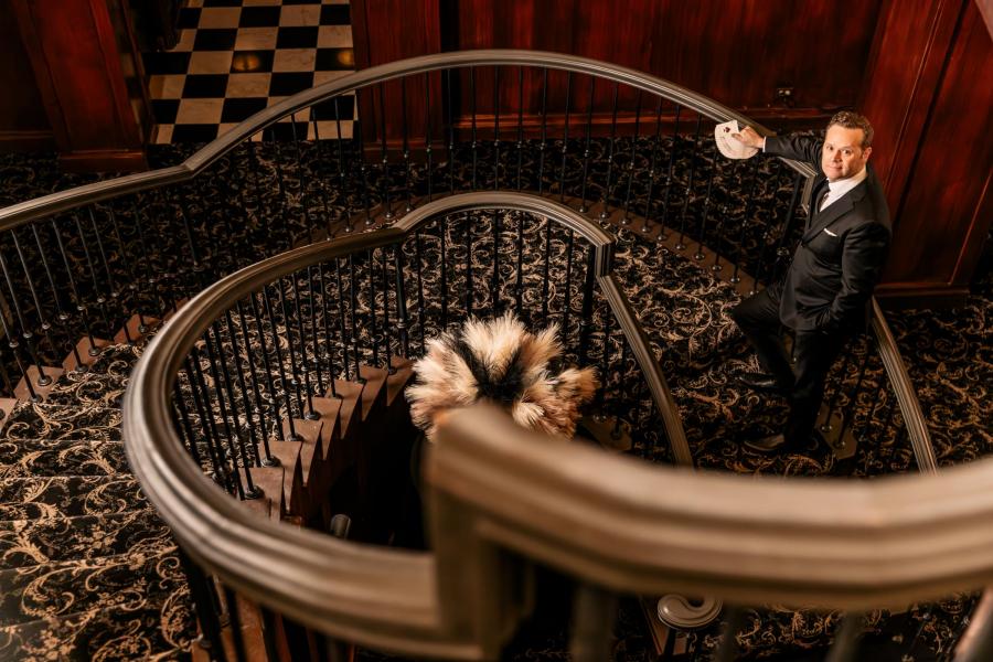 Dennis stands at the bottom of a spiral staircase at The Magic Parlour.