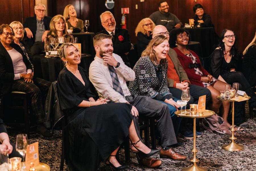 A room of audience members laughing and smiling. 