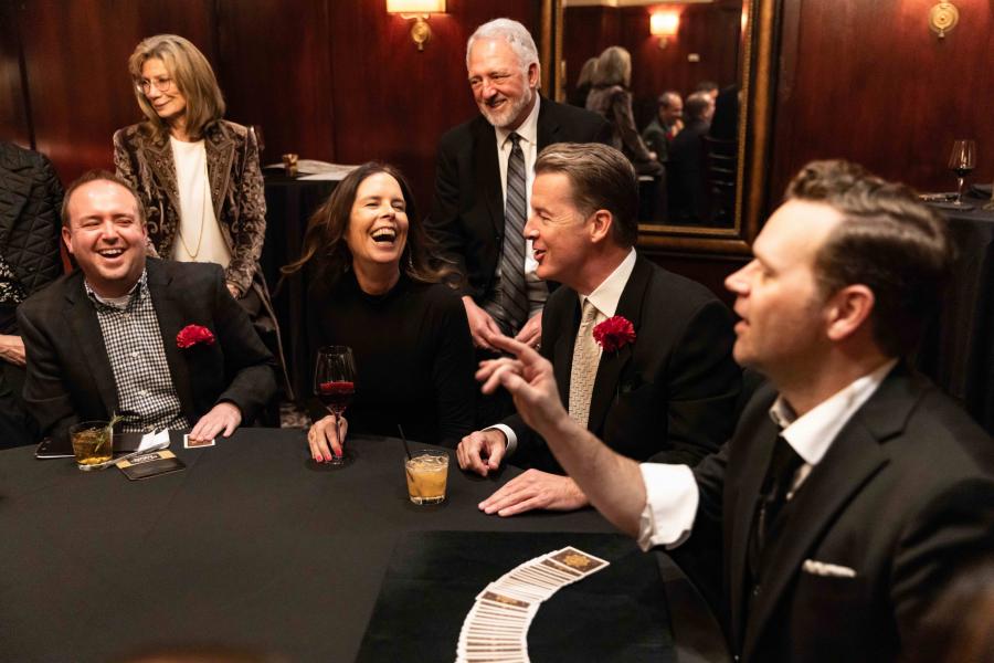 Dennis performing magic at a table for a small group of audience members.