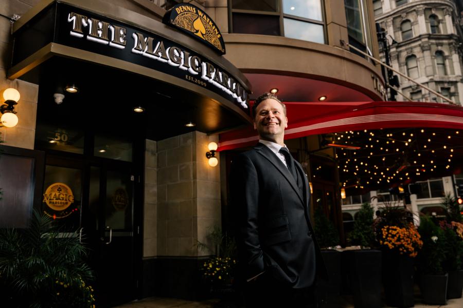 Dennis smiling in front of The Magic Parlour marquee. 